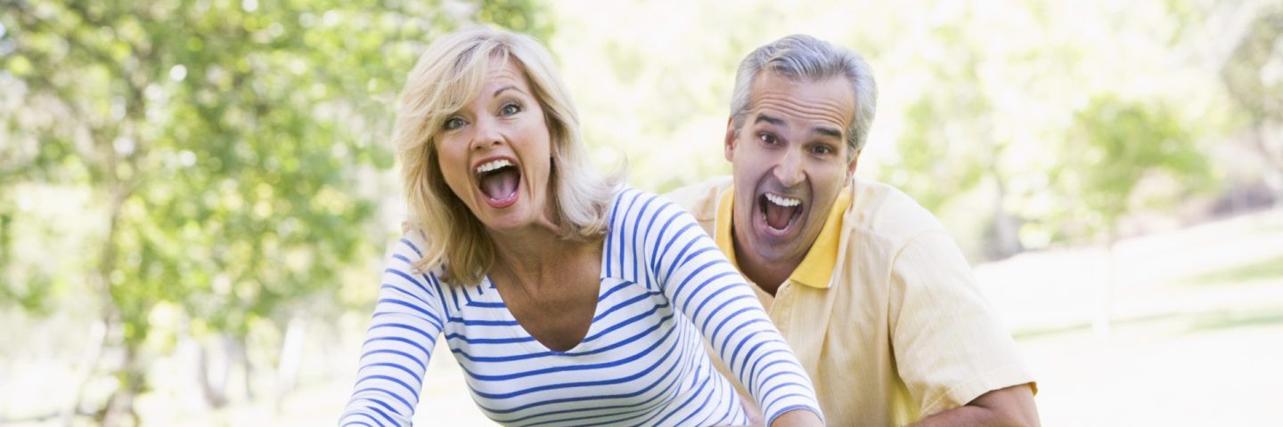 Couple on bike outdoors smiling and acting scared