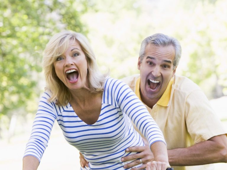 Couple on bike outdoors smiling and acting scared