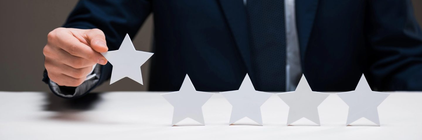 cropped view of businessman holding star isolated on grey, quality concept