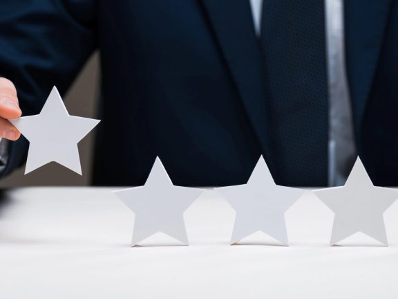 cropped view of businessman holding star isolated on grey, quality concept