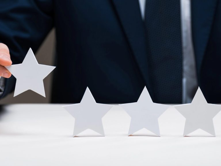 cropped view of businessman holding star isolated on grey, quality concept