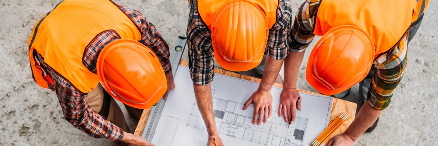 high angle view of group of builders discussing building plan at construction site