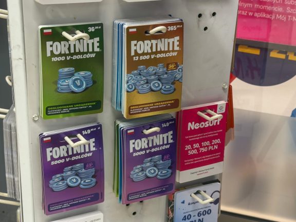 Poznan, Poland - November 22, 2025: Physical Fortnite V-DOLCOW digital currency cards and Neosurf prepaid payment vouchers for various online transactions