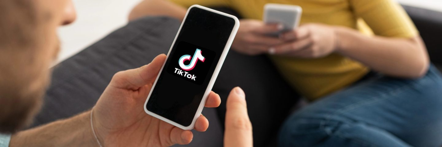 KYIV, UKRAINE - FEBRUARY 21, 2020: Selective focus of man holding smartphone with TikTok app near woman at home