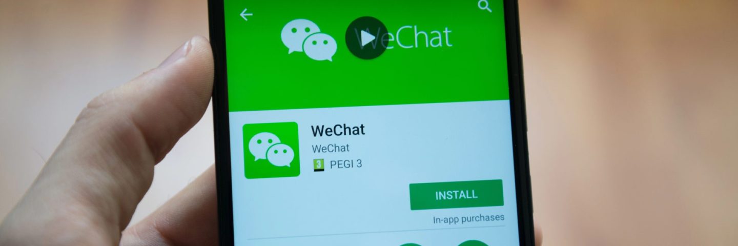 Man hand holding smartphone with WeChat application in google play store