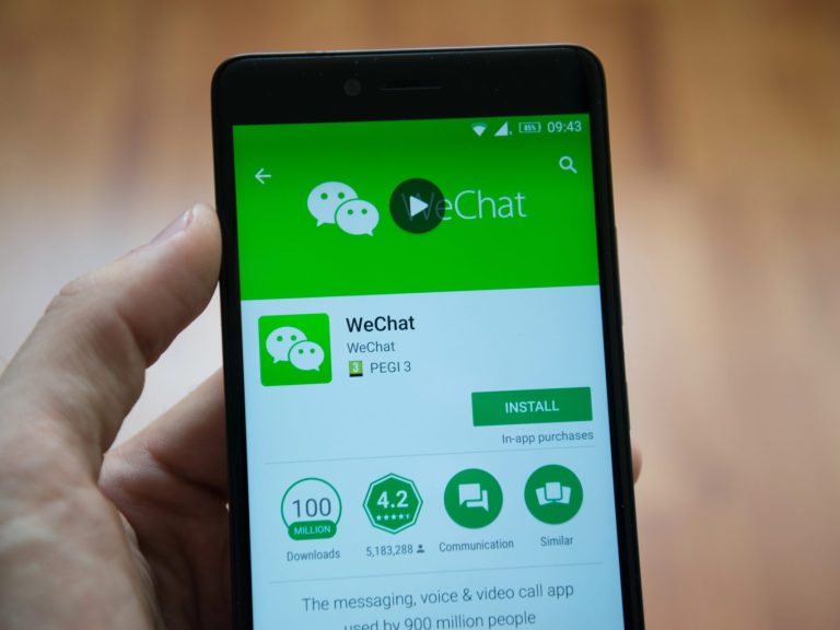 Man hand holding smartphone with WeChat application in google play store