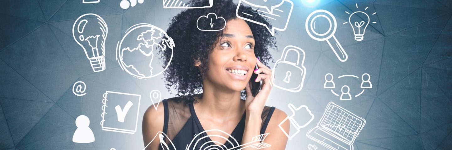 Smiling african american woman talking on phone standing near dark gray wall with white computer and internet drawing. Toned image double exposure