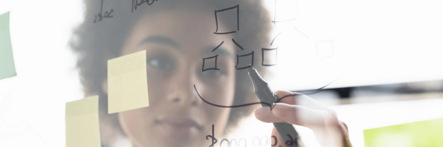 Blurred african american businesswoman writing on glass board