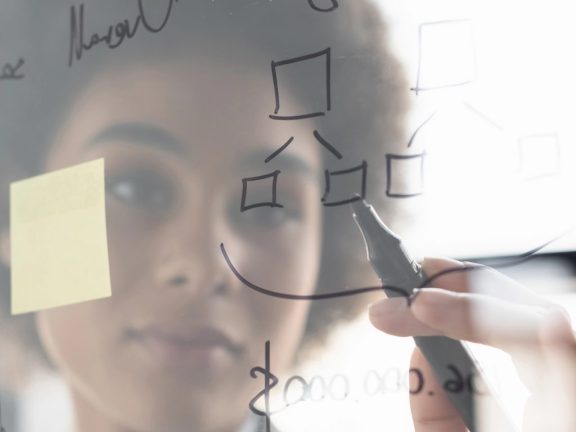 Blurred african american businesswoman writing on glass board