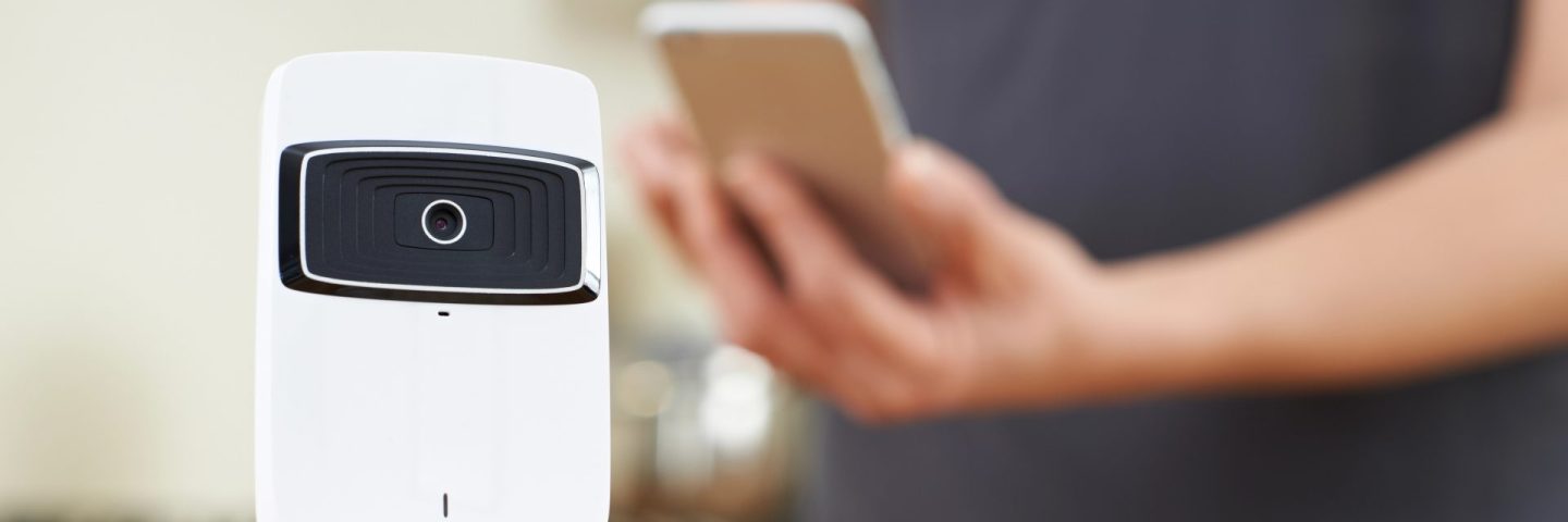 Woman Controlling Smart Security Camera Using App On Mobile Phon