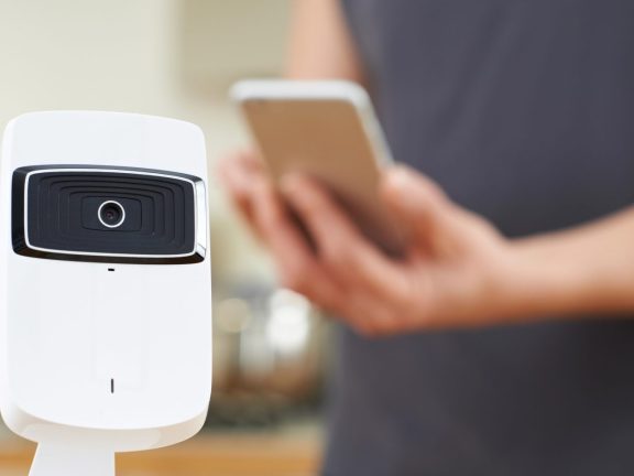 Woman Controlling Smart Security Camera Using App On Mobile Phon