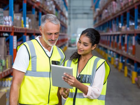 Warehouse workers discussing with digital tablet