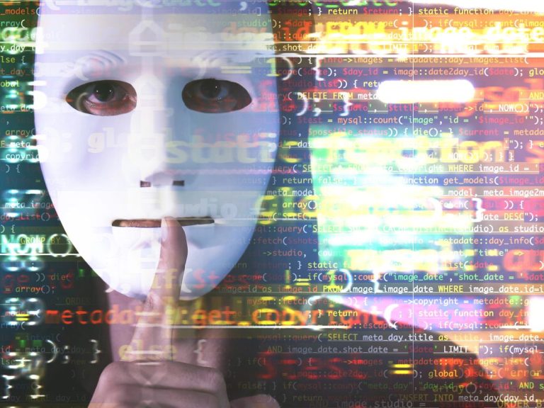 Hacker in mask showing silence gesture and code on blurred background. Concept of cyber attack and security