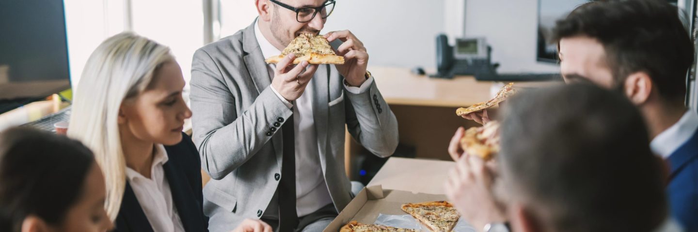A group of businesspeople having pizza for lunch at meeting room.