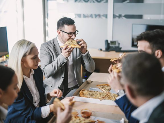 A group of businesspeople having pizza for lunch at meeting room.