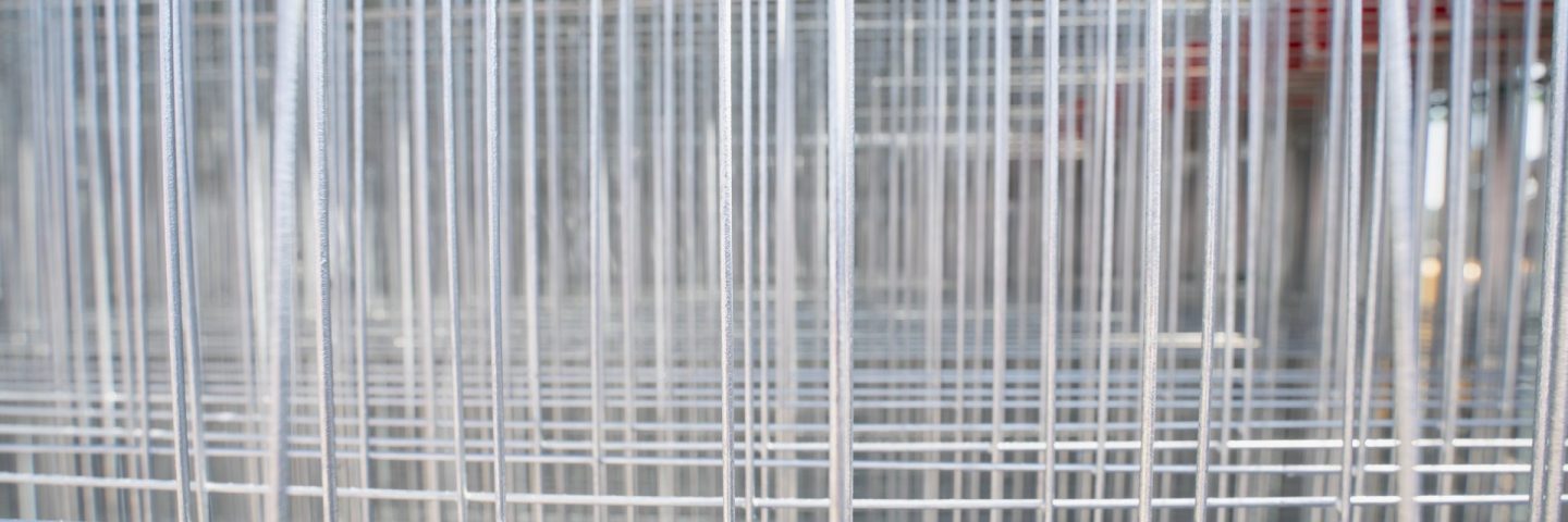 Modular galvanized steel wire grid fencing stored in industrial yard, illustrating equipment inventory, property barrier, and site safety